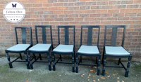 a set of four black dining chairs in front of a brick wall