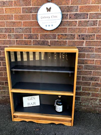 a wooden bookcase with a sign on it next to a brick wall