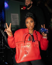 a woman holding a red purse and a cell phone