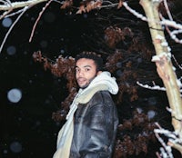 a man in a leather jacket standing in the snow