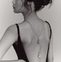 a black and white photo of a woman with a necklace on her back