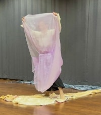 a woman in a purple dress is standing on a wooden floor