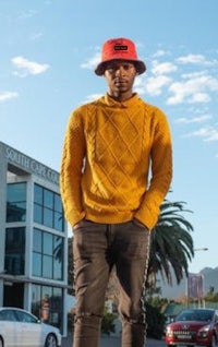 a man in a yellow sweater standing in front of a car