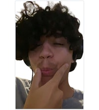 a man with curly hair is putting his finger on his lips