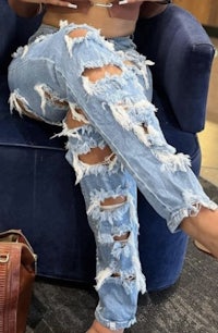 a woman sitting on a couch in ripped jeans