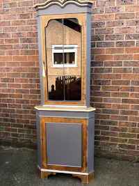 a grey and wood corner cabinet with a mirror
