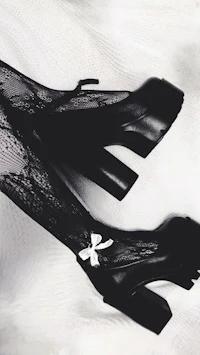 a pair of black boots with lace and bows