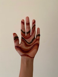 a person's hand painted with a red and brown pattern