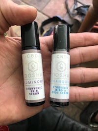 two bottles of essential oils in a person's hand