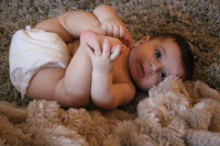 a baby laying on a blanket with his feet up
