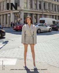 a woman is standing on a city street in a jacket and shorts
