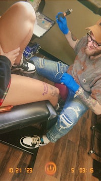 a man is getting a tattoo on his leg