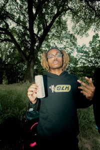 a man with dreadlocks holding a can of soda