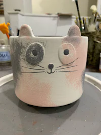 a ceramic pot with a cat face on it