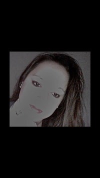 a woman is posing in front of a dark background