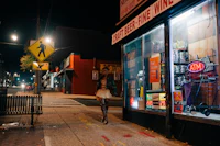 a woman walking down a sidewalk at night