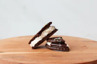 two chocolate oreos sitting on top of a wooden board