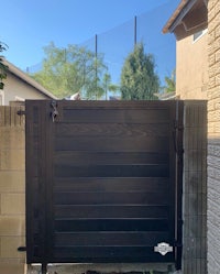 a black gate in a backyard with a fence