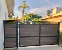 a wooden gate in front of a house with palm trees