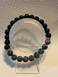 a bracelet with black and pink beads on a clear surface