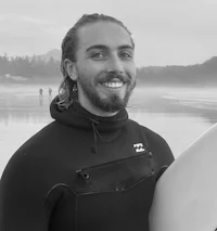 a man in a wetsuit holding a surfboard