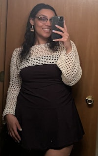 a woman in glasses taking a selfie in a mirror