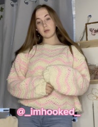 a girl wearing a pink sweater and jeans