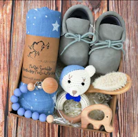 a blue baby shower gift box with a teddy bear, baby shoes and a wooden rattle