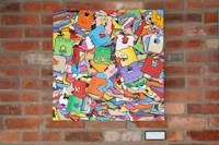 a colorful painting hanging on a brick wall
