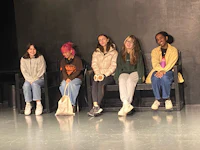 a group of girls sitting on chairs on a stage