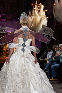 a woman is walking down the runway in a wedding dress with wings