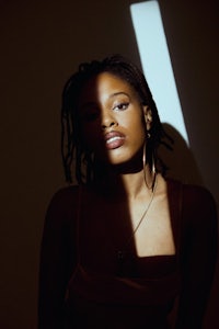 a woman with dreadlocks posing in front of a light
