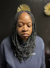 a woman with braided hair standing in front of a wall