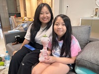 a woman and a girl sitting on a couch holding a vase