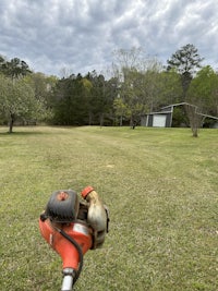 a lawn mower on a grassy field with trees in the background