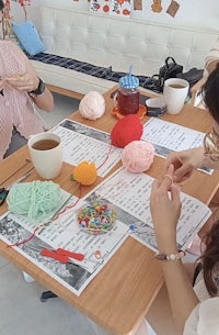 a group of people sitting around a table knitting