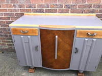 a grey and wood sideboard in front of a brick wall