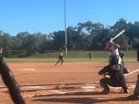 a softball player swinging a bat on a field