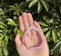 a person's hand holding a bracelet with the word'baby'on it