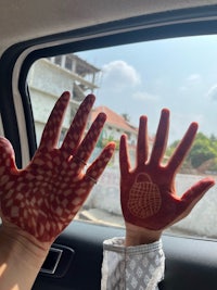 two hands with henna painted on them in a car