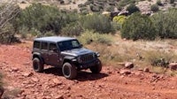 a black jeep is driving down a rocky trail