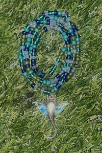 a blue and green beaded necklace with a dolphin pendant