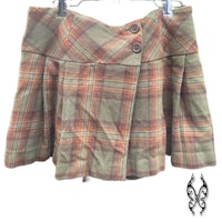an orange and brown plaid skirt hanging on a hanger