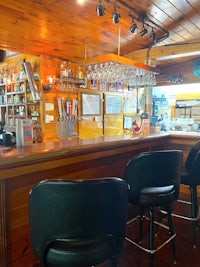 a bar in a wooded area with black stools
