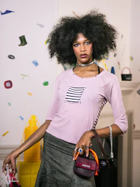 a woman in a pink top and skirt holding a purse