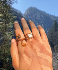 a woman's hand holding a ring with a cat on it