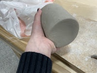 a person holding a clay ball on a table