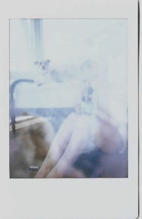 a polaroid of a woman sitting on a bed