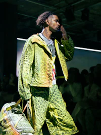 a man walking down a runway with a bag