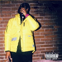 a man in a yellow jacket is leaning against a brick wall